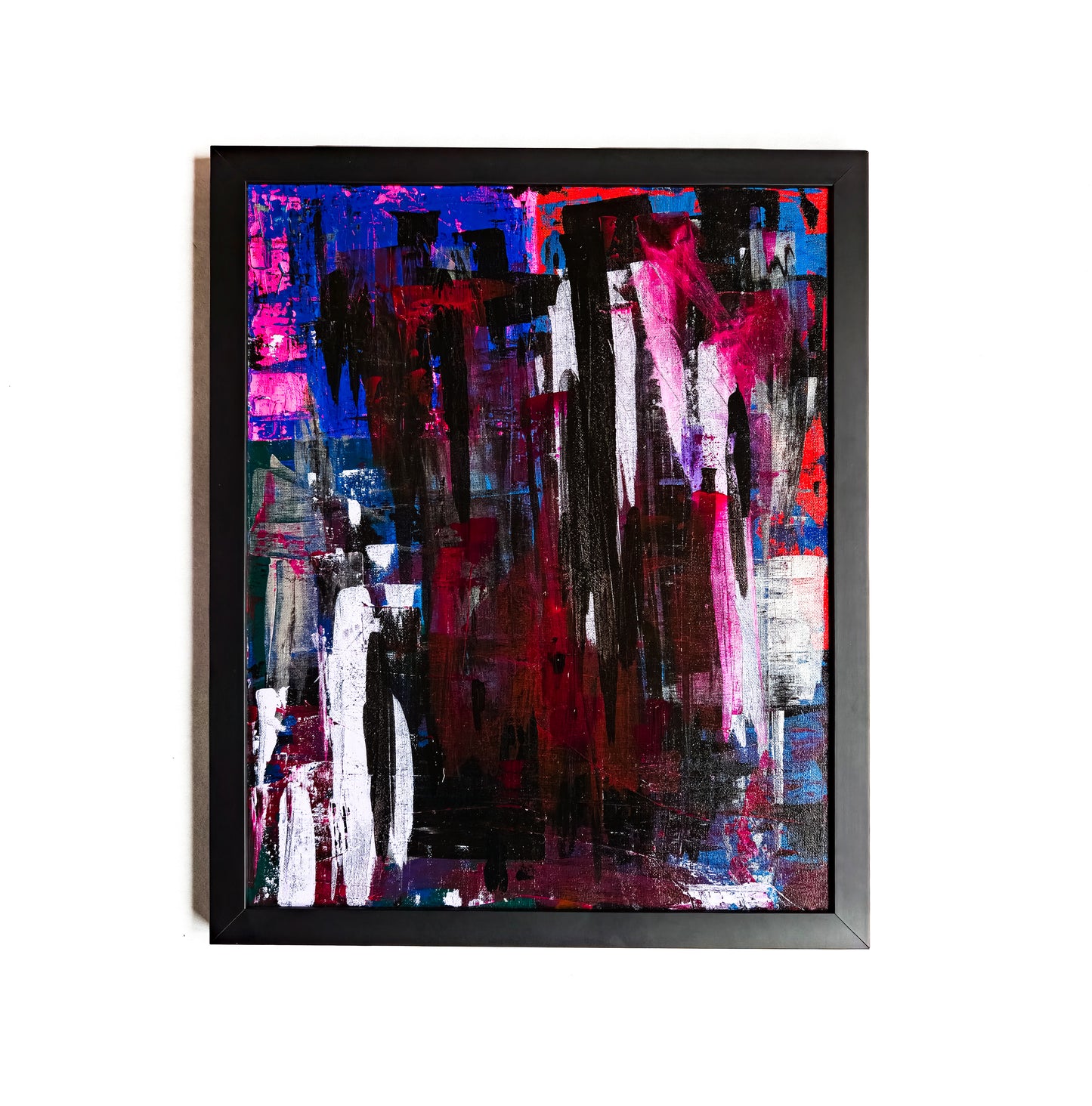 A framed abstract painting featuring a variety of dark and bright colors, with no discernible figures or shapes, primarily in a black, blue, red, and white palette.